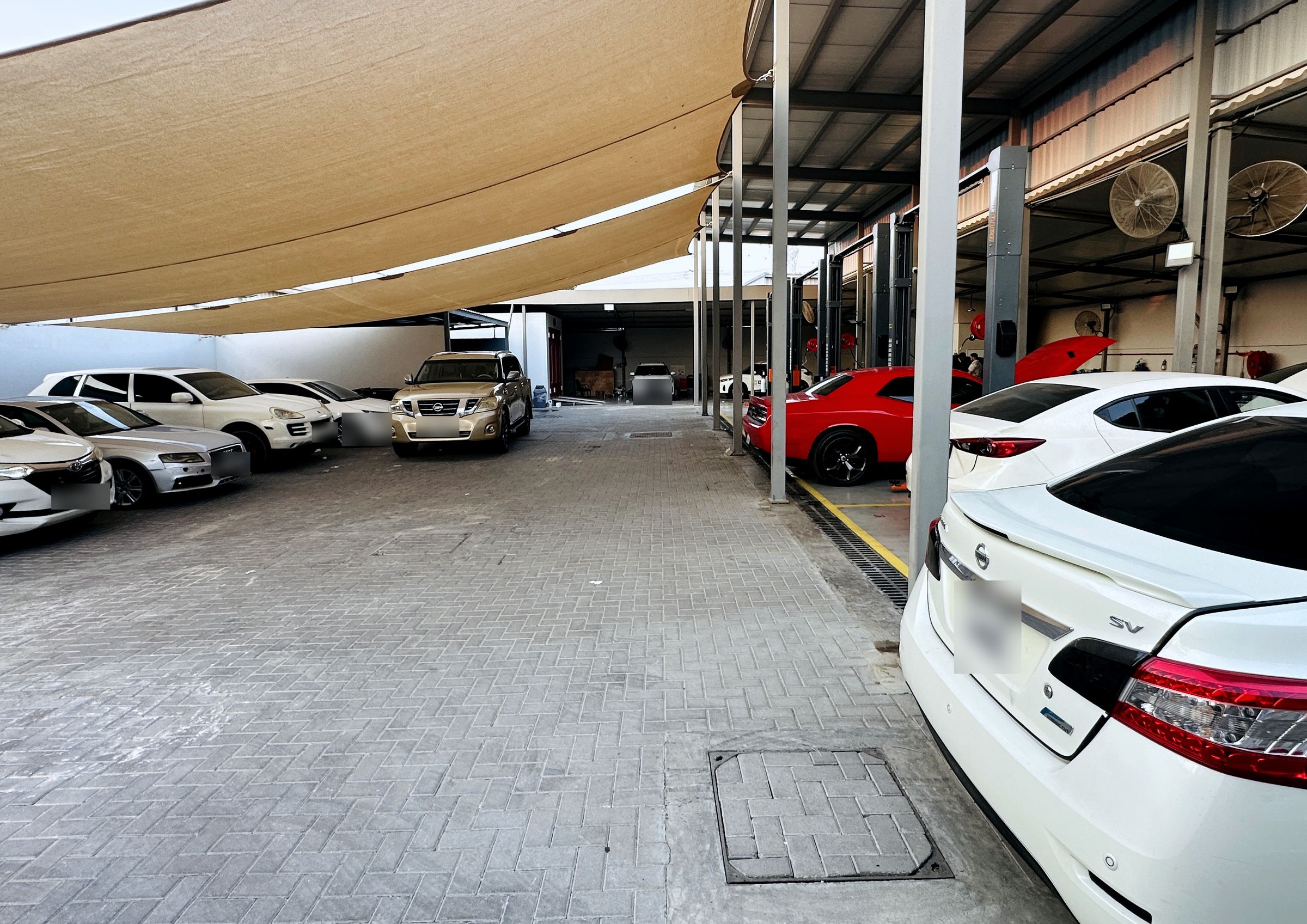 Shaded yard with customer and fleet vehicles parked beside the service bays