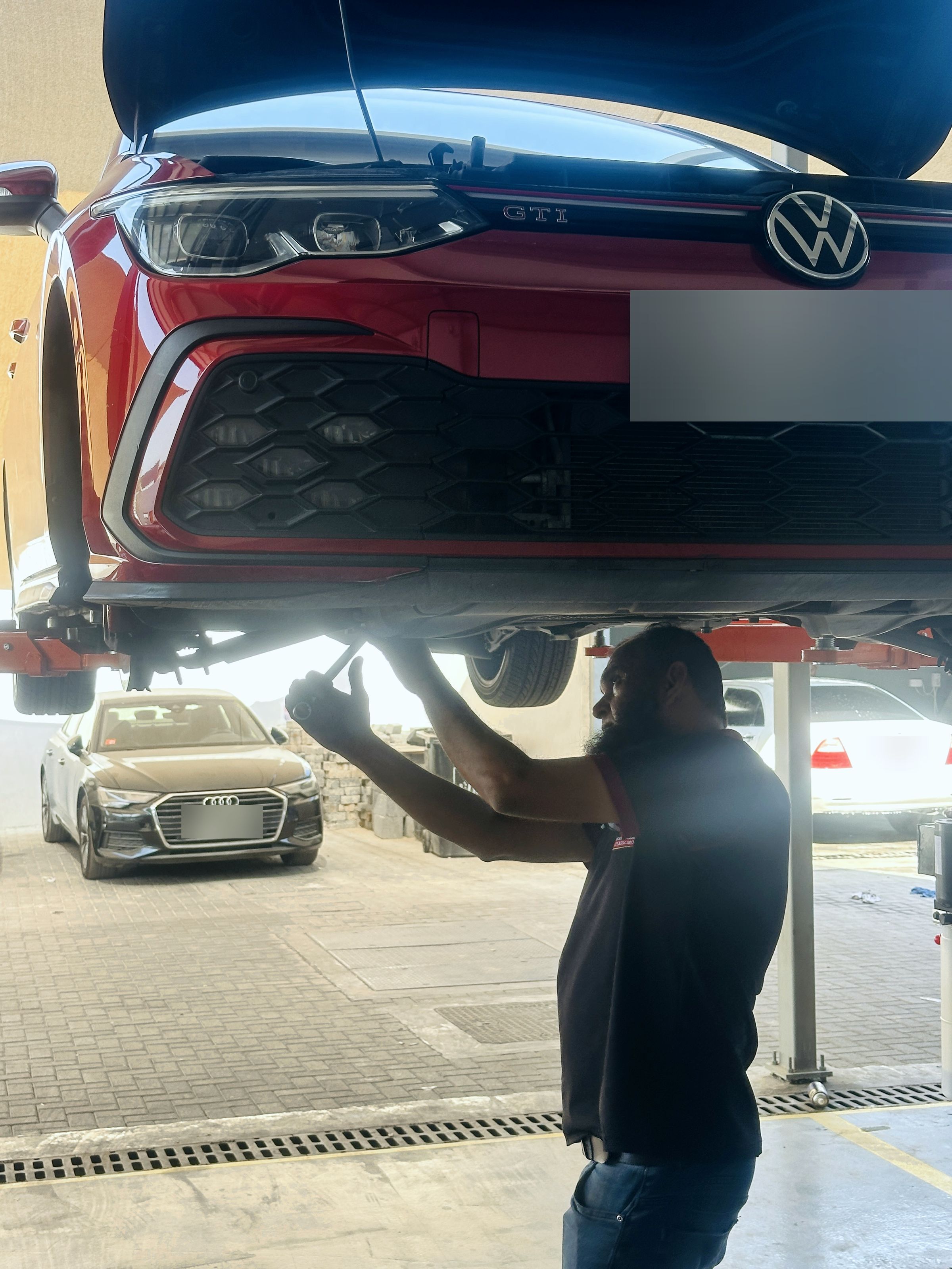 Technician working underneath a Volkswagen Golf GTI raised on a lift